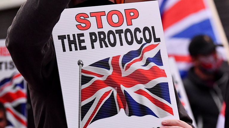 A Loyalist demonstrator holds a sign and a cell phone during a protest against the Northern Ireland protocol as a result of Brexit, in Belfast, Northern Ireland, September 17, 2021. REUTERS/Clodagh Kilcoyne